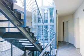 A modern interior with a metal staircase, a glass railing, and a door leading to another room. - LUXURY 12B - Porto - Piscina - Jacuzzi (Santo Stefano al Mare)