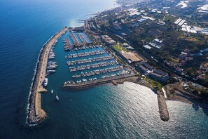 An aerial view of a marina with numerous boats docked, surrounded by residential and commercial buildings.