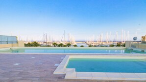 Une piscine sur le toit offrant une vue sur un port de plaisance et des bateaux.