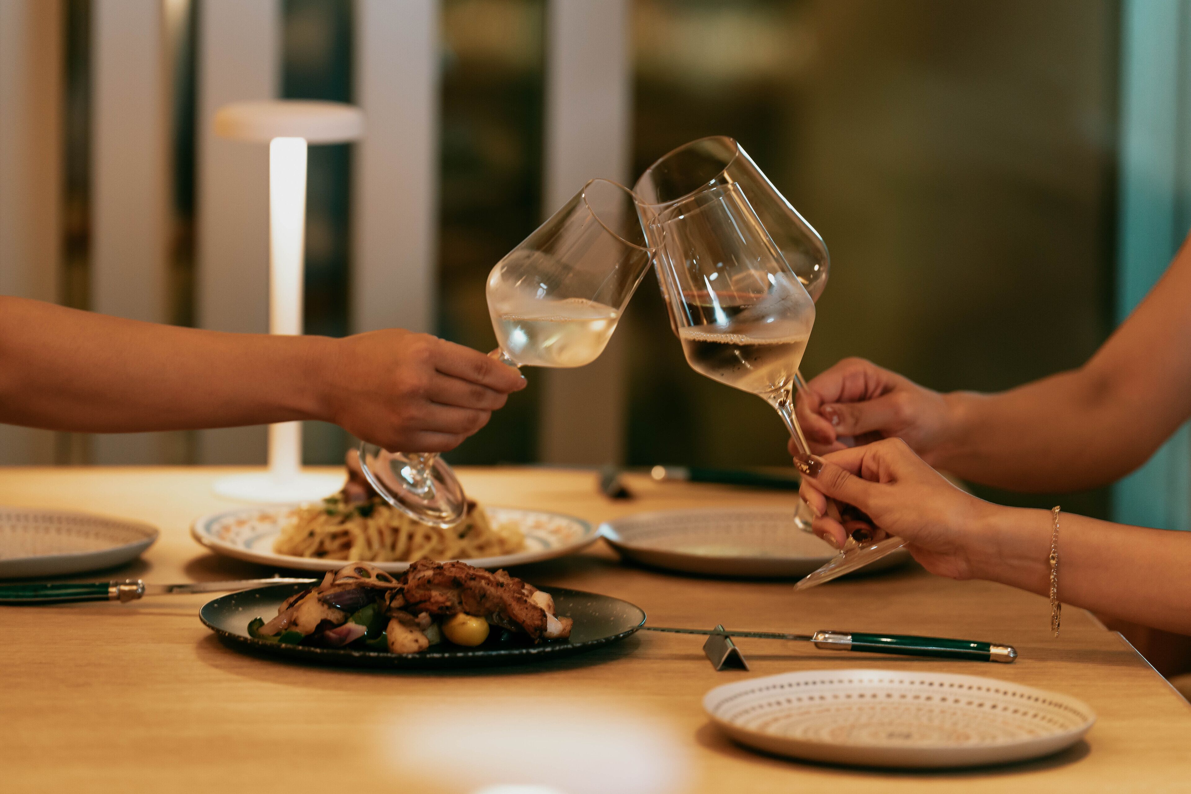 Una mesa de comedor con platos de comida, vasos y cubiertos.