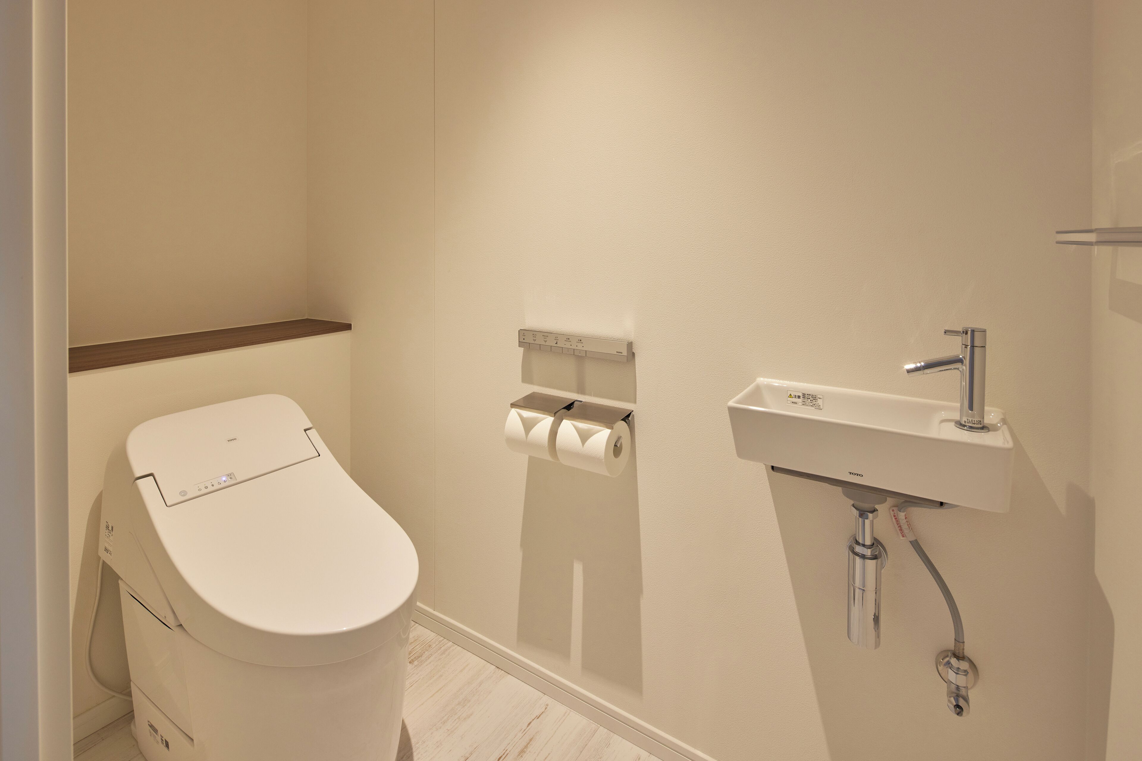 Un baño moderno con inodoro, dispensador de papel higiénico y lavamanos.