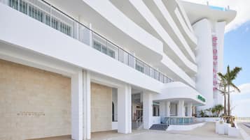 Un hotel moderno con varios pisos, una escalera destacada y un área de piscina.