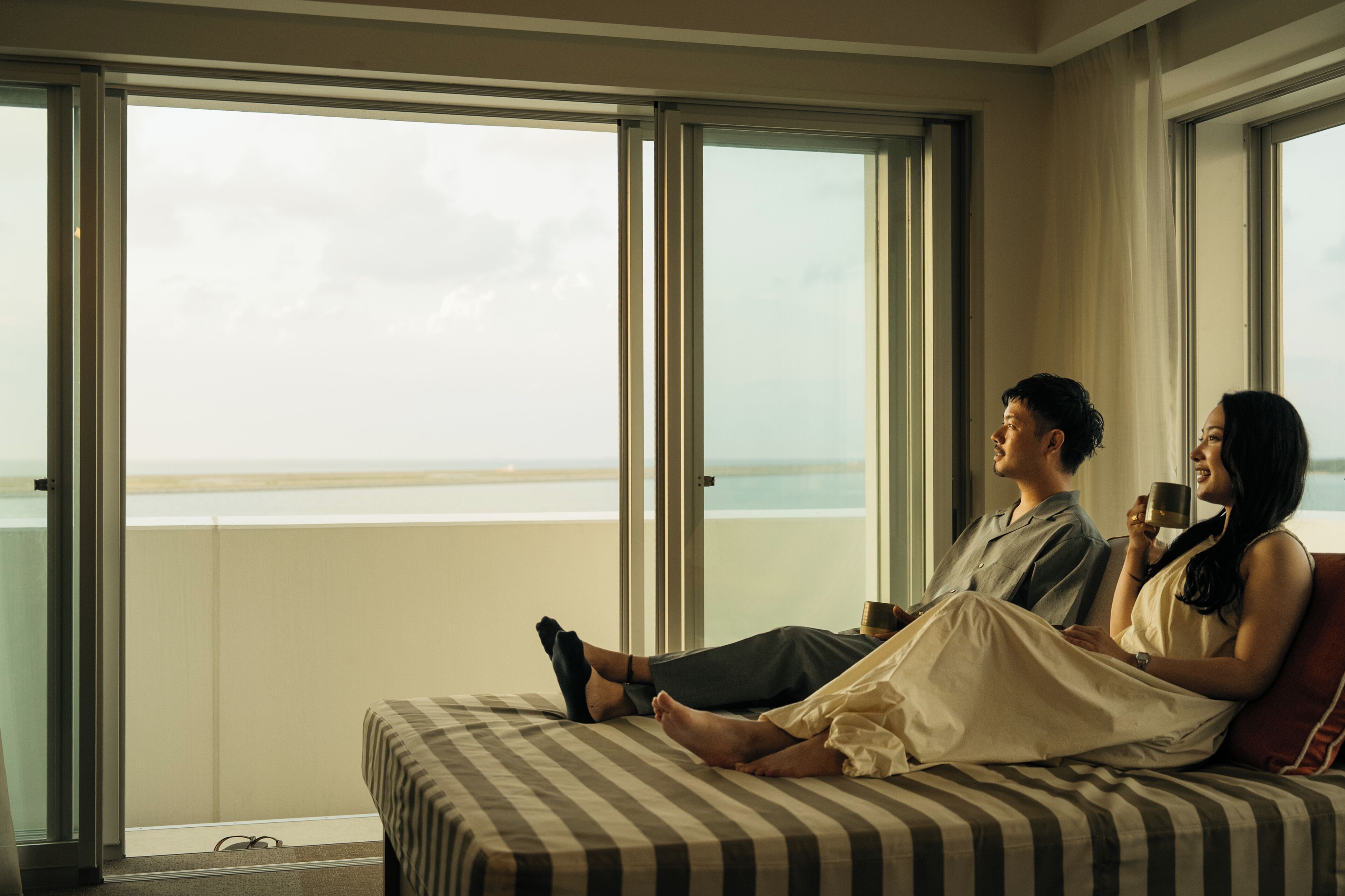 Ein Zimmer mit einem Bett, großen Fenstern und Blick aufs Meer.