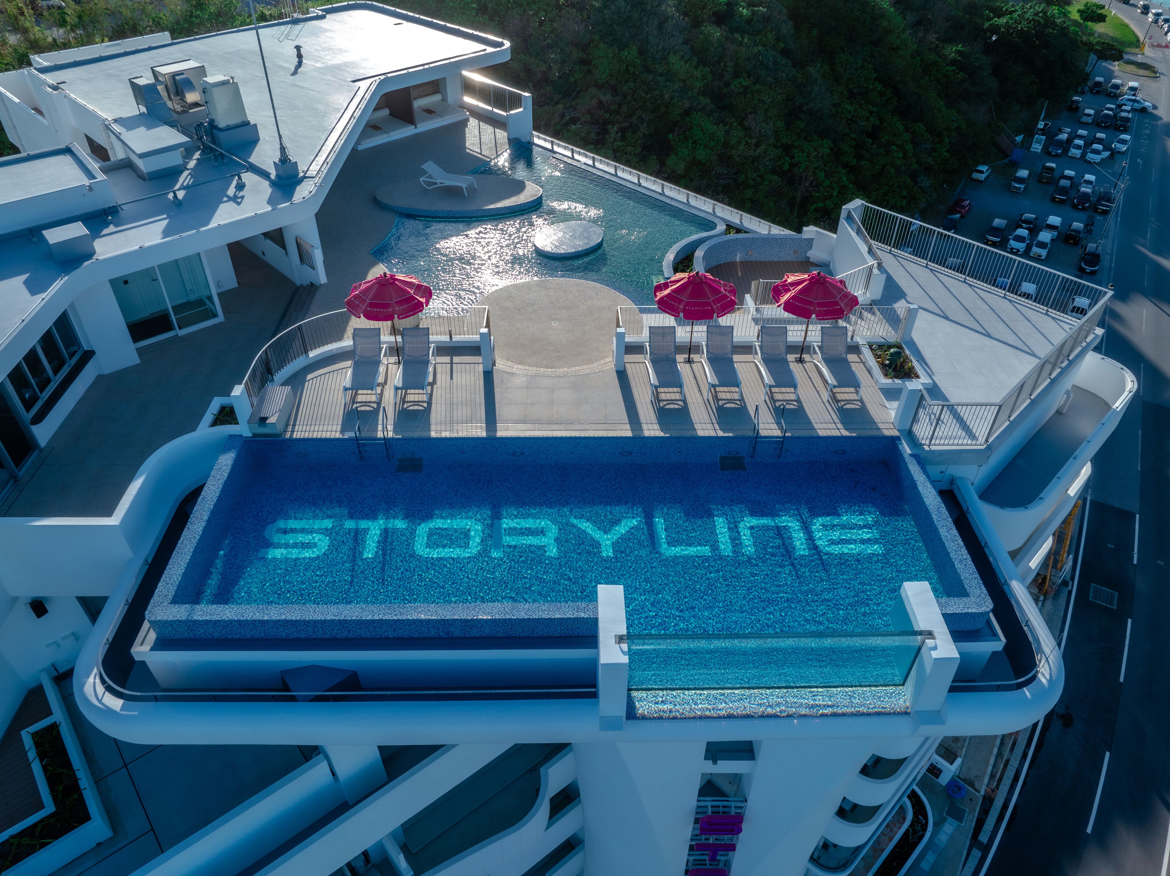 A rooftop pool area with lounge chairs and umbrellas, and the words "STORYLINE" visible on the pool's edge.