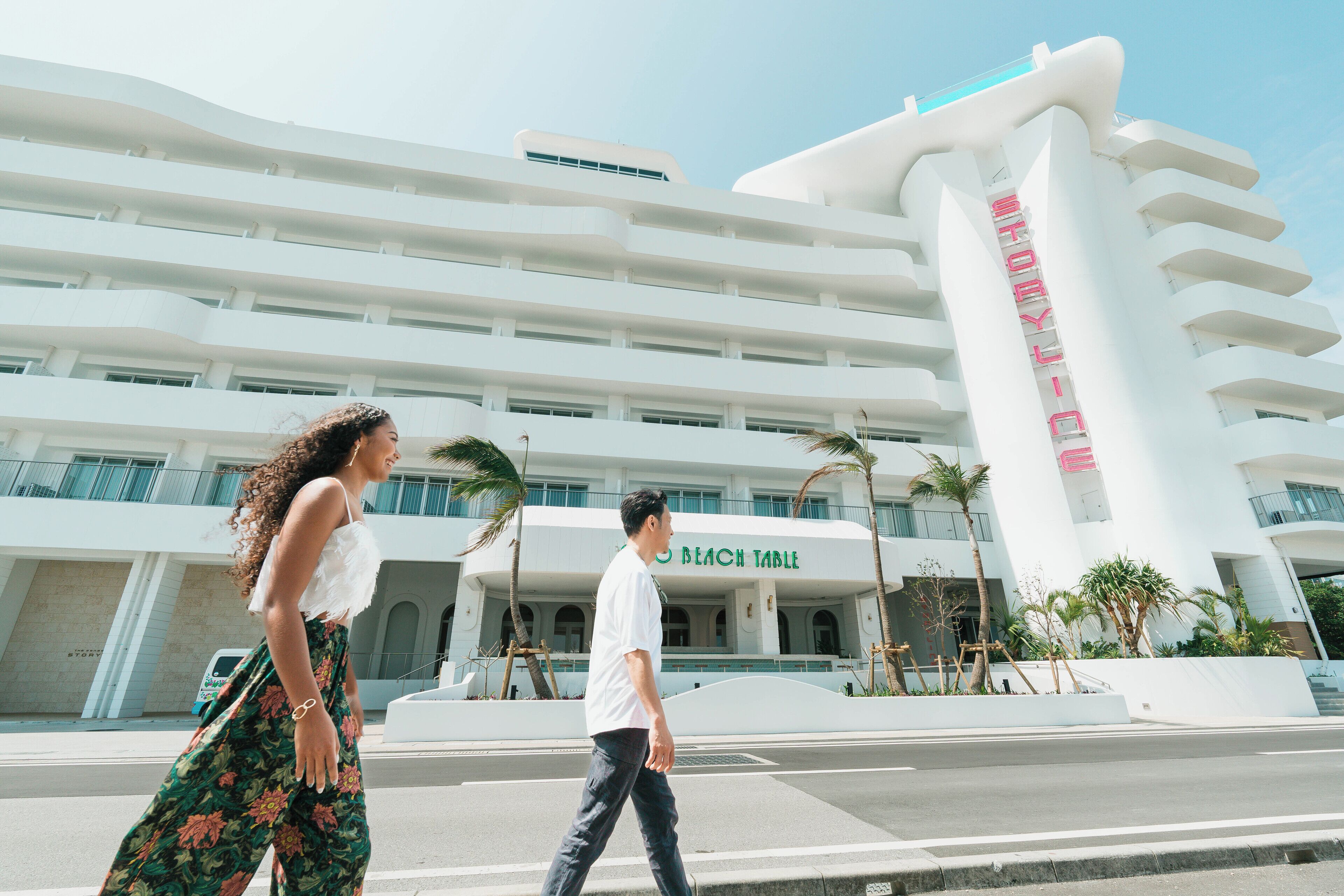A modern hotel with a prominent 'Beach Table' sign, featuring a multi-story structure with balconies and palm trees.