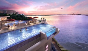 Una piscina infinita en la azotea con vistas al mar y al atardecer.