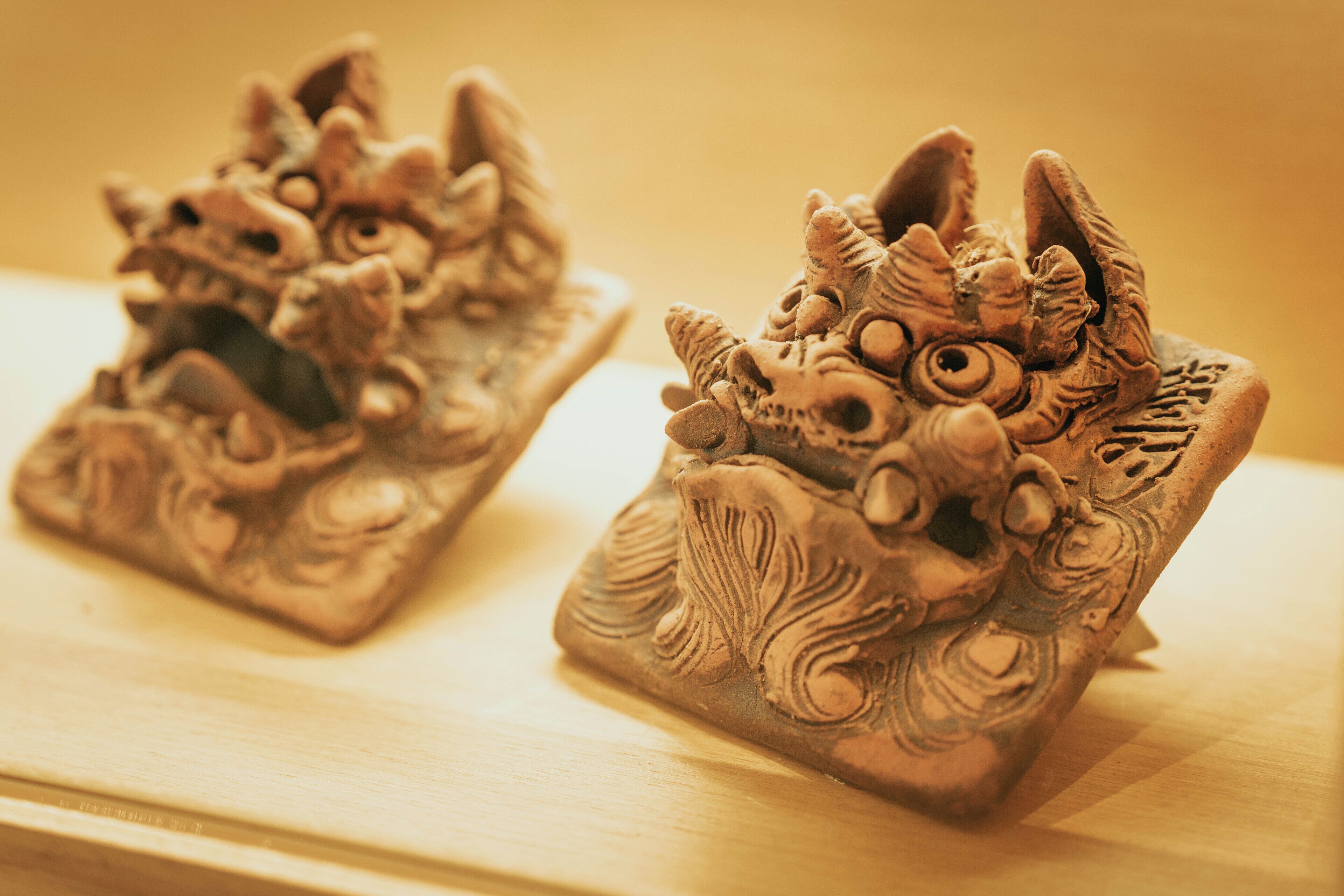 Two intricately carved sculptures on a wooden surface.
