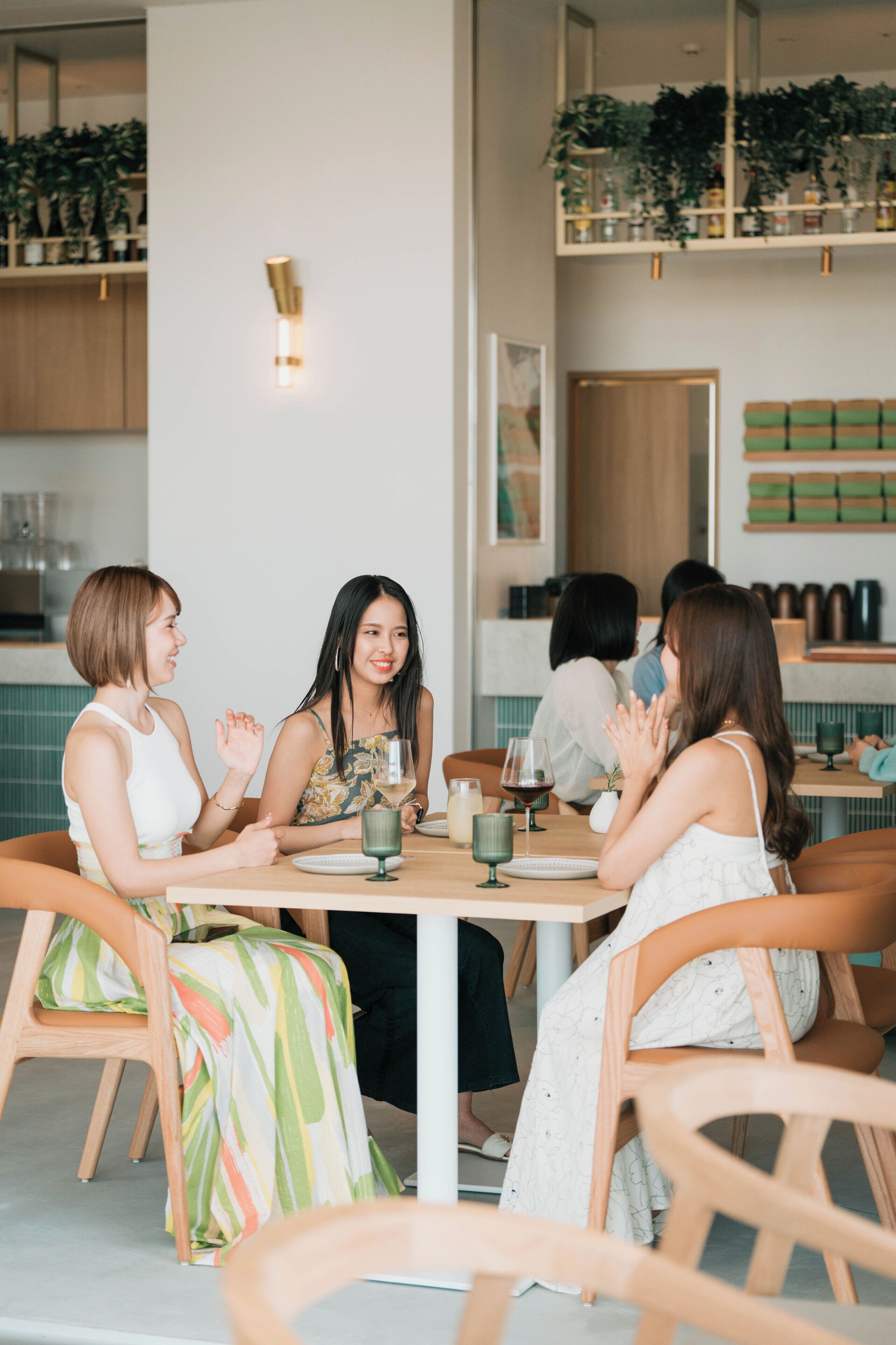 A group of people seated around a table in a modern interior with wooden chairs and a white table.