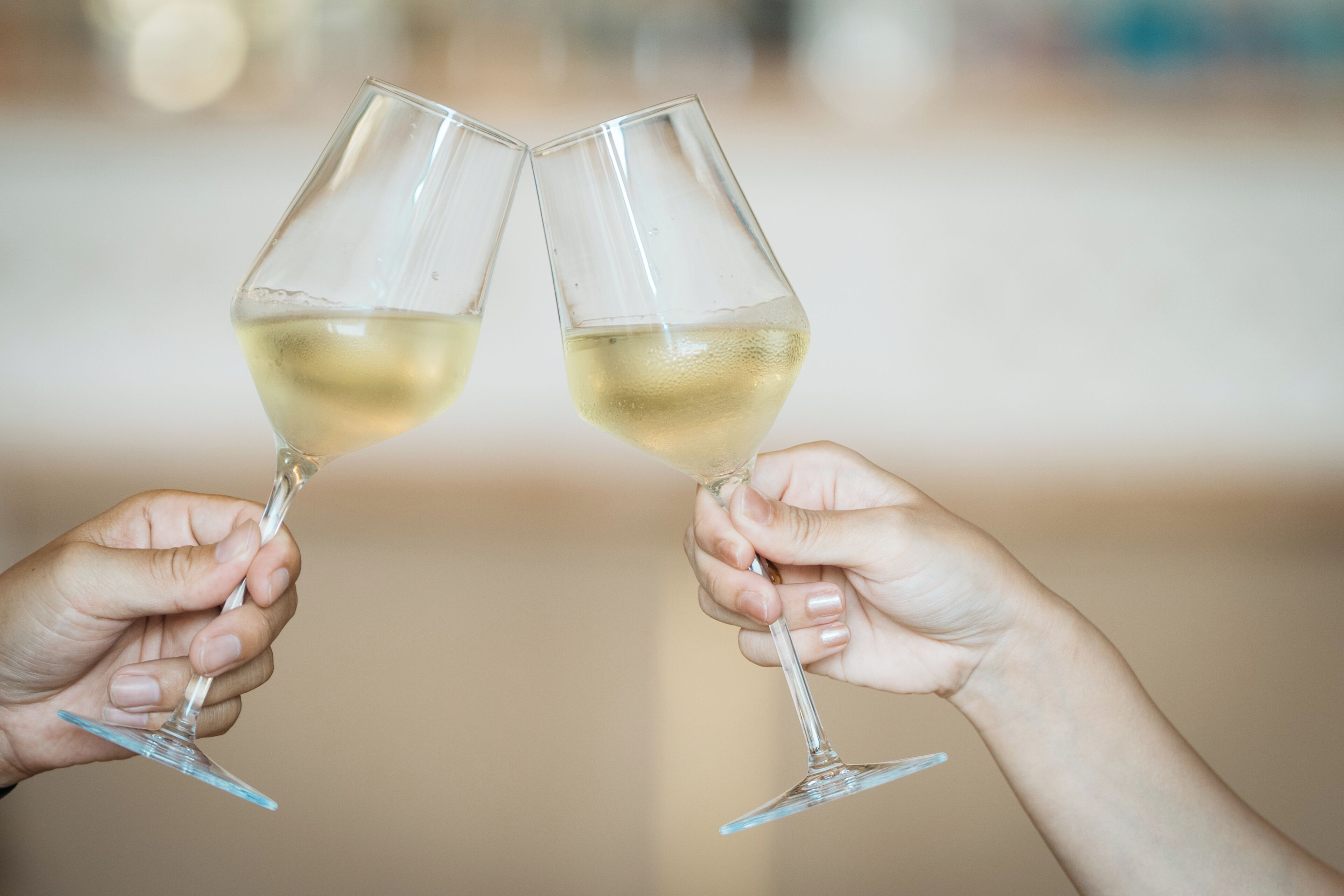 Two hands holding wine glasses.
