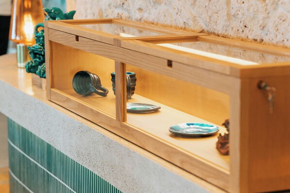 Un aparador de madera con puerta de cristal que contiene utensilios de cocina y objetos decorativos.