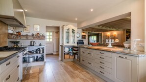 Une cuisine spacieuse dotée d’un plancher en bois, d’un îlot central et de meubles de rangement intégrés.