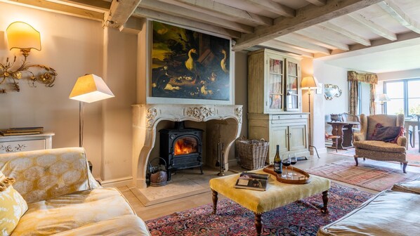 Un salon chaleureux avec une cheminée, des fauteuils confortables et un grand tableau accroché au mur.