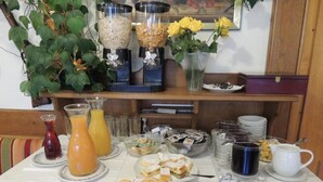 Monipuolinen aamiaisbuffet, jossa on tarjolla erilaisia ruokia, juomia ja kahvia.