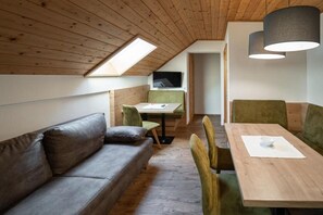 Um quarto estilo loft acolhedor, com teto de madeira, sofá, mesa de jantar e cadeiras.