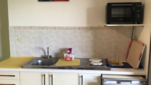 Een compacte keuken met een spoelbak, magnetron en kleine koelkast.