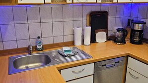 Une cuisine moderne dotée d’un évier en acier inoxydable, d’un lave-vaisselle encastré, d’une cuisinière et d’armoires en bois.