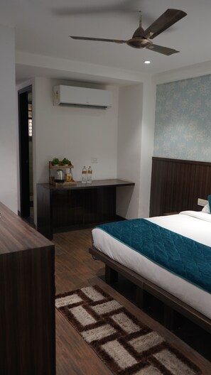 A modern hotel room with a bed, a desk, and a ceiling fan. - Qotel Hotel Rajouri Garden (New Delhi)