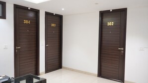 Three dark wooden doors with numbers 304, 303, and 302. - Qotel Hotel Rajouri Garden (New Delhi)