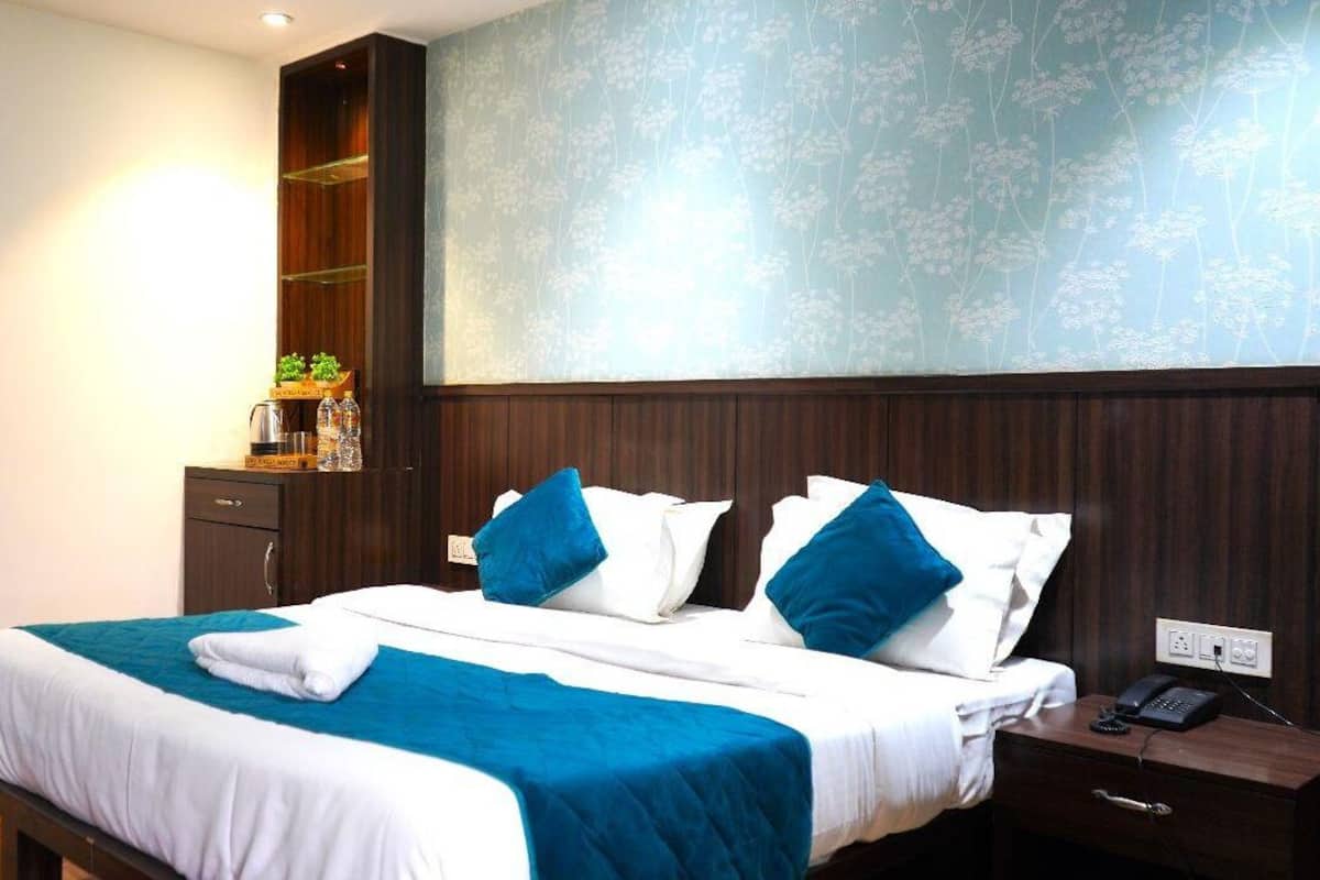A hotel room with a bed, a nightstand, a telephone, and a shelf with toiletries.