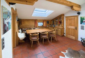 A rustic kitchen with a wooden table and chairs, a skylight, and wooden cabinets. - Buccara Apartments (Kitzbuhel)
