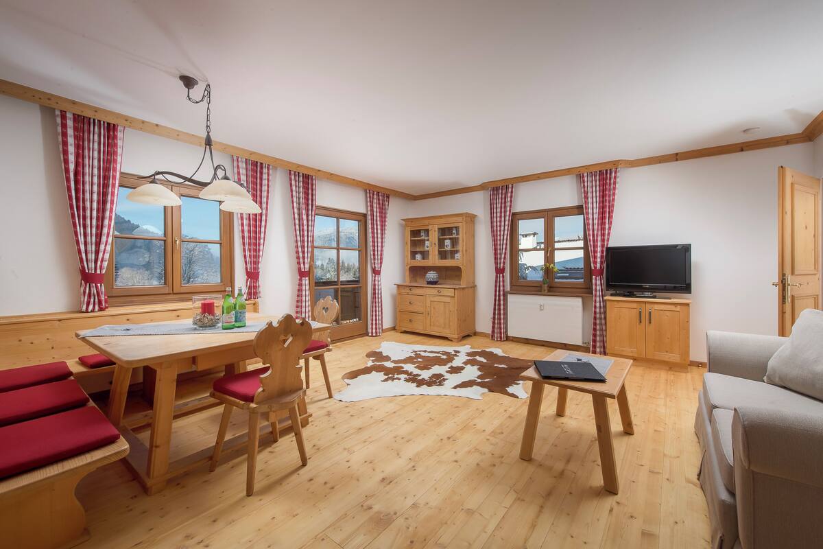 A cozy living room with wooden furniture, a cowhide rug, and a television.