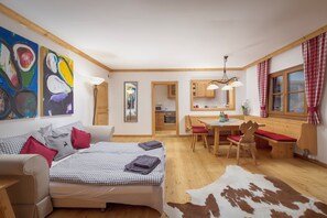 A cozy room with a bed, a dining table, and a kitchen area. - Buccara Apartments (Kitzbuhel)