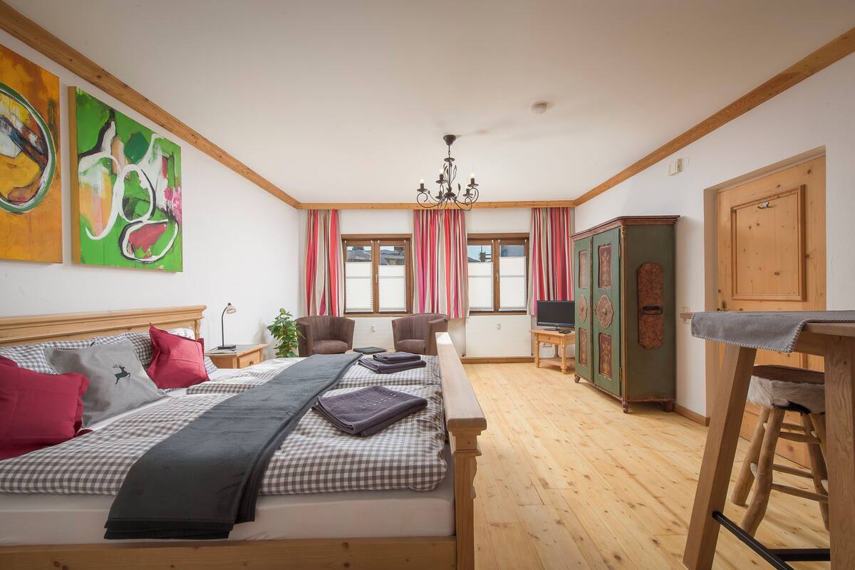 A bedroom with a bed, a nightstand, a chair, a TV, and a cabinet.