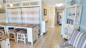 Een keuken met een eettafel, stoelen en een bordje met de tekst 'BEACH HOUSE'.