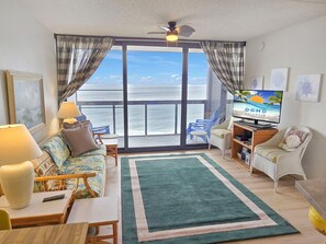 Relax in this ocean-view living room with a sofa, chairs, flat-screen TV, and ceiling fan.