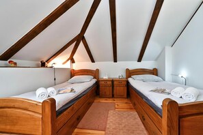 A bedroom with two wooden beds, a small wooden nightstand, a night lamp, and a brick-patterned rug. - Hunting Lodge (Velika Pisanica)