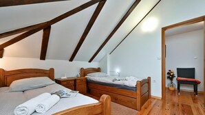 A bedroom with a wooden bed, a nightstand, a dresser, a wooden ceiling with beams, a small table with a vase, and a chair. - Hunting Lodge Hills Retreat (Velika Pisanica)