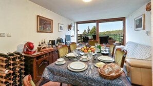 A dining area with a table set for four, a wine rack, and a view of the outdoors. - Hunting Lodge Hills Retreat (Velika Pisanica)