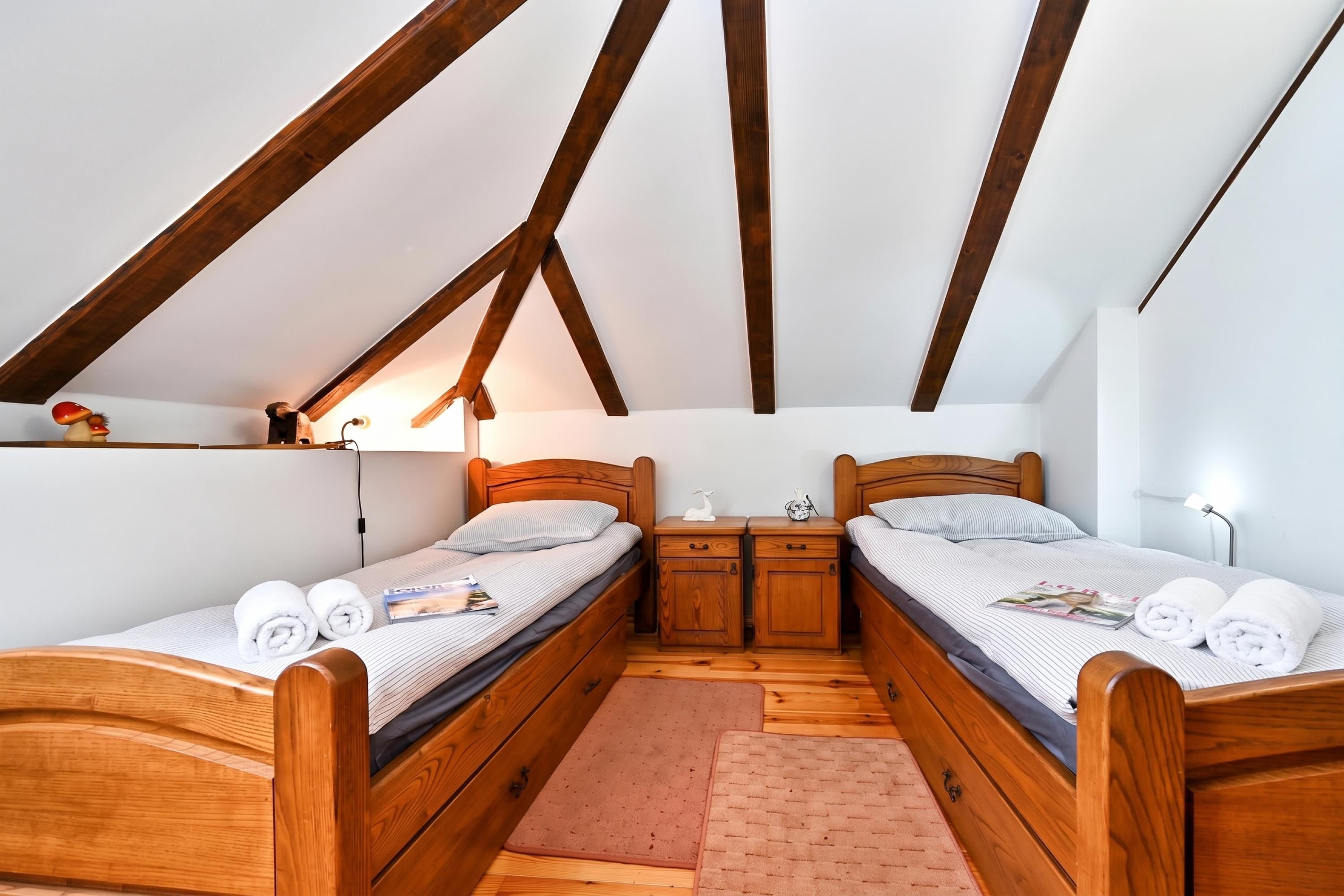 Un dormitorio con dos camas de madera, techo de madera y una mesita de noche con lámpara.