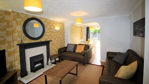 A living room with a fireplace, two sofas, a coffee table, and a mirror on the wall.