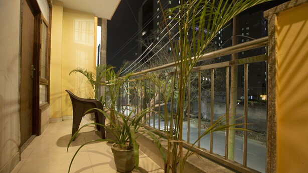 A balcony with potted plants, a chair, and a view of the street at night. - Hotel Glinzer Palace By Aura (Noida)