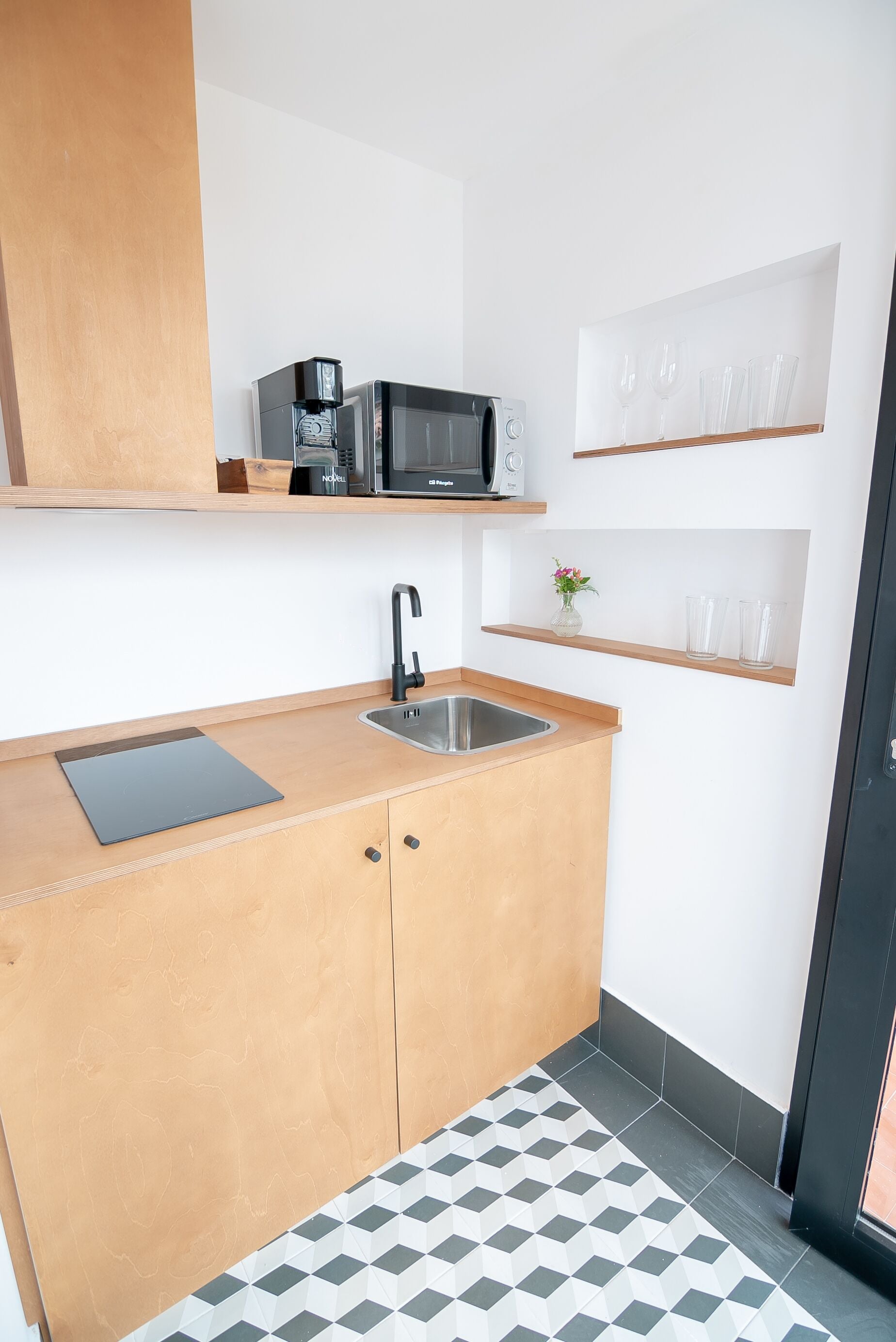 A compact kitchen with a microwave, sink, and wooden cabinets.