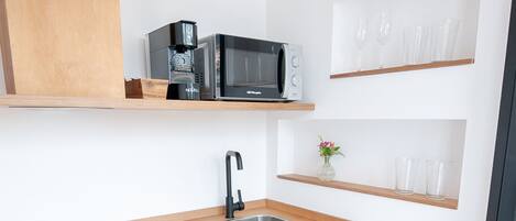 A compact kitchen with a microwave, sink, and wooden cabinets.