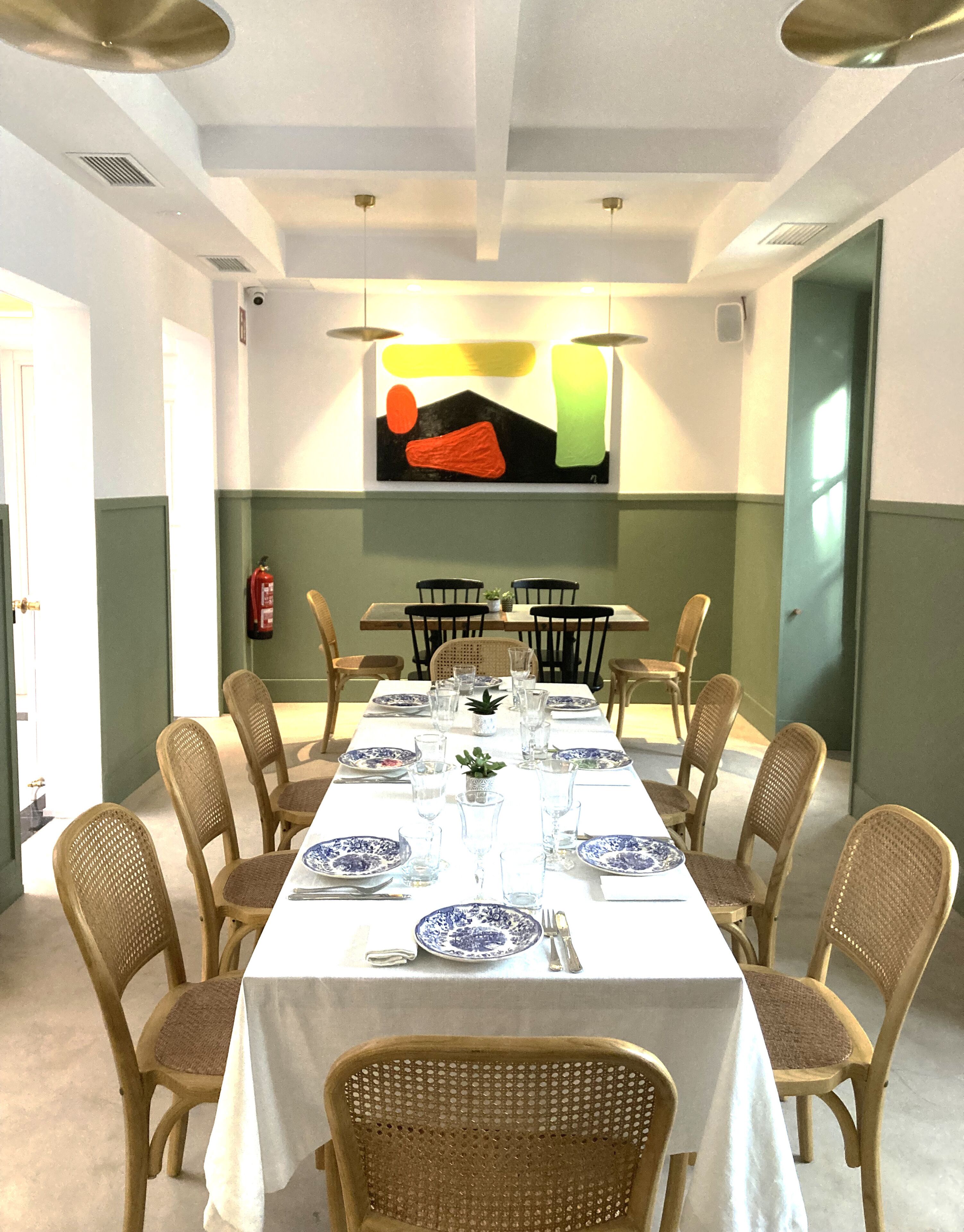 A dining room with a long table set for six, surrounded by wicker chairs.