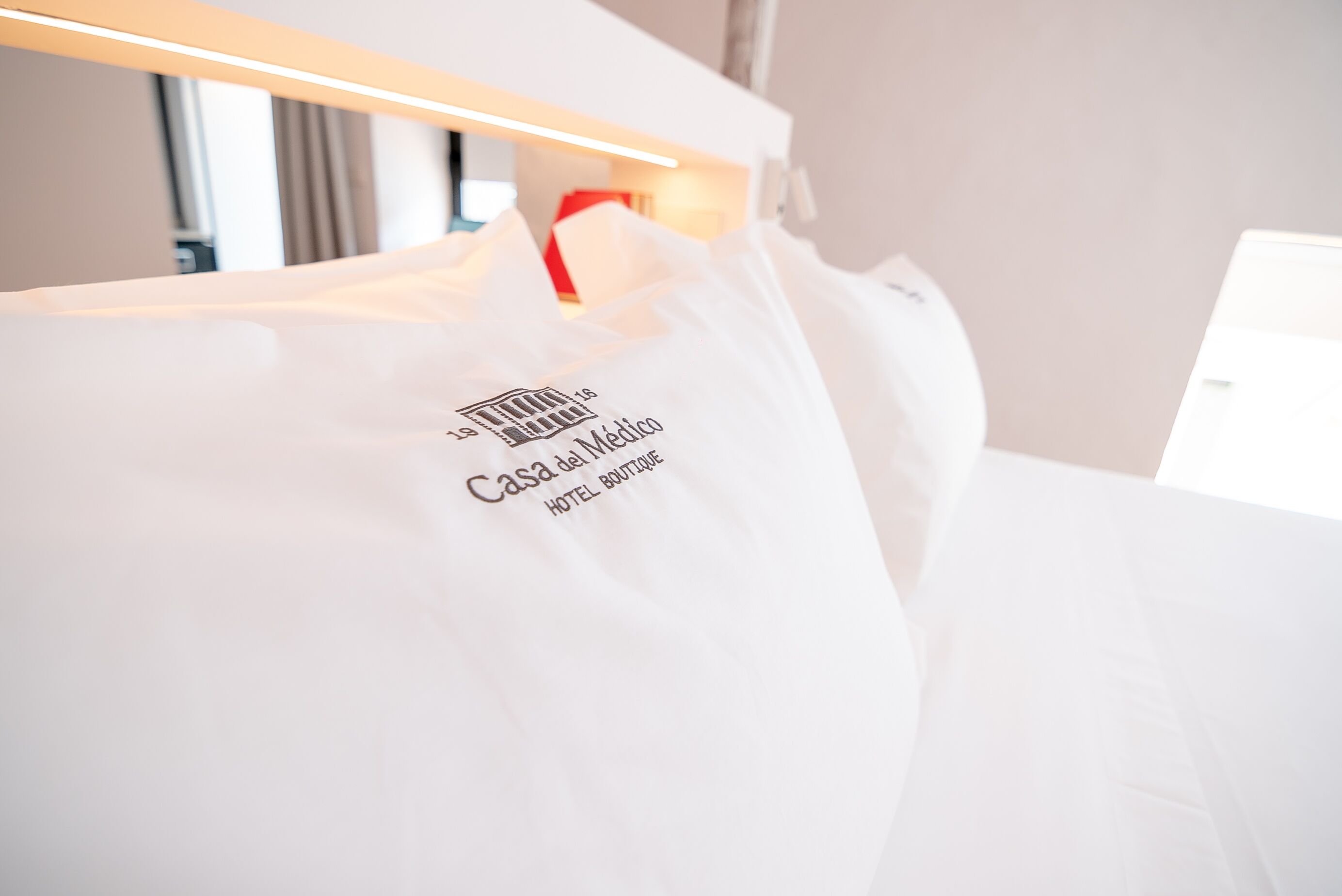 Habitación de hotel blanca con una cama y una bolsa blanca colgada en ella.