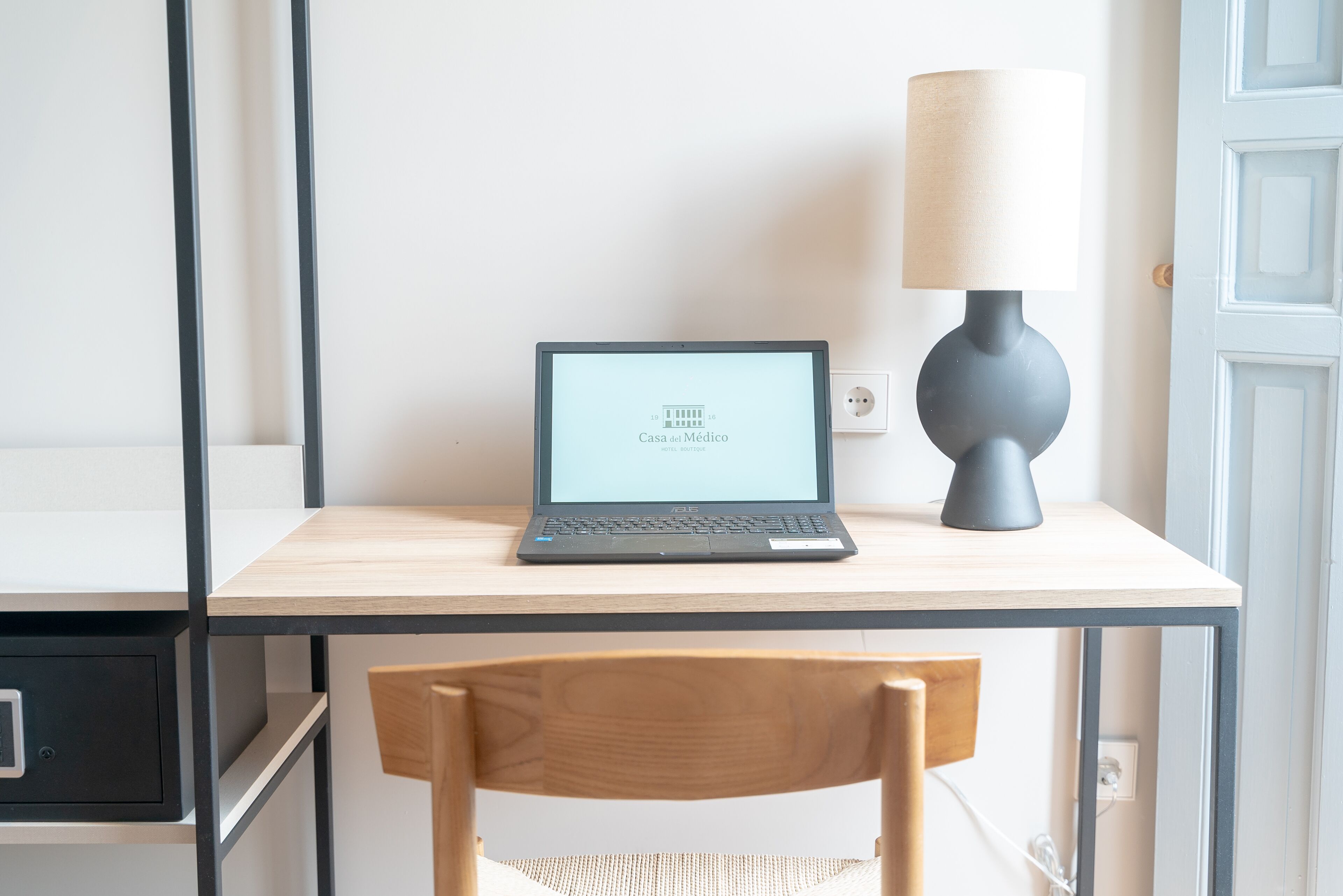 A laptop on a wooden desk with a lamp beside it.