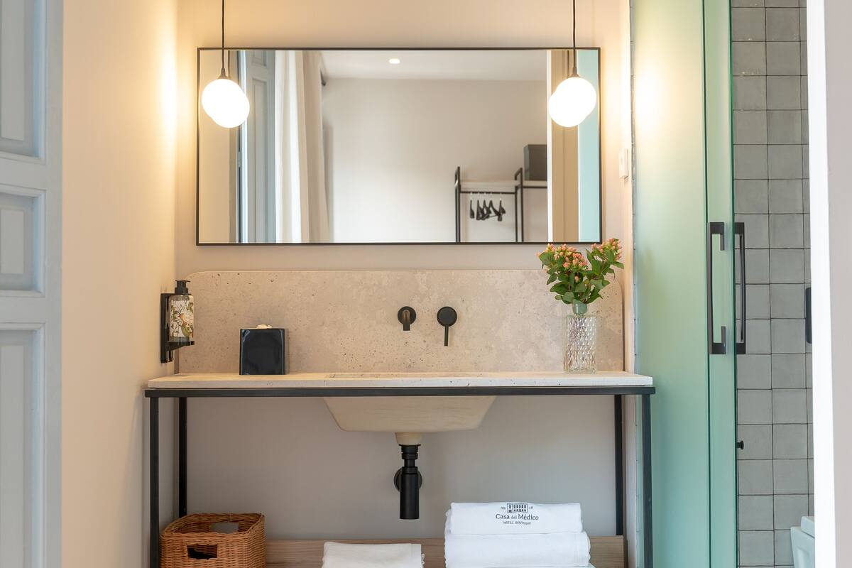 A modern bathroom with a wooden vanity, a large mirror, and a shower area.