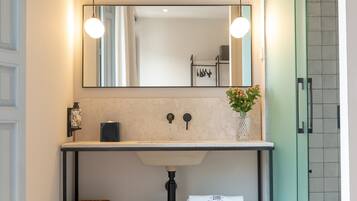 Un baño moderno con tocador de madera, un espejo grande y zona de ducha.