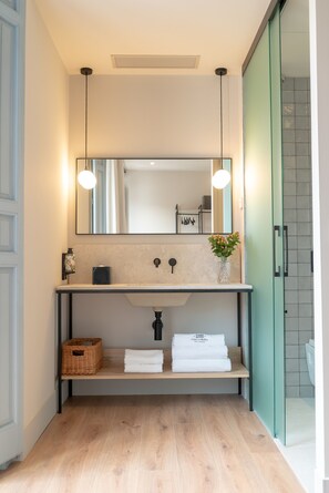 A modern bathroom with a wooden vanity, a large mirror, and a shower area.