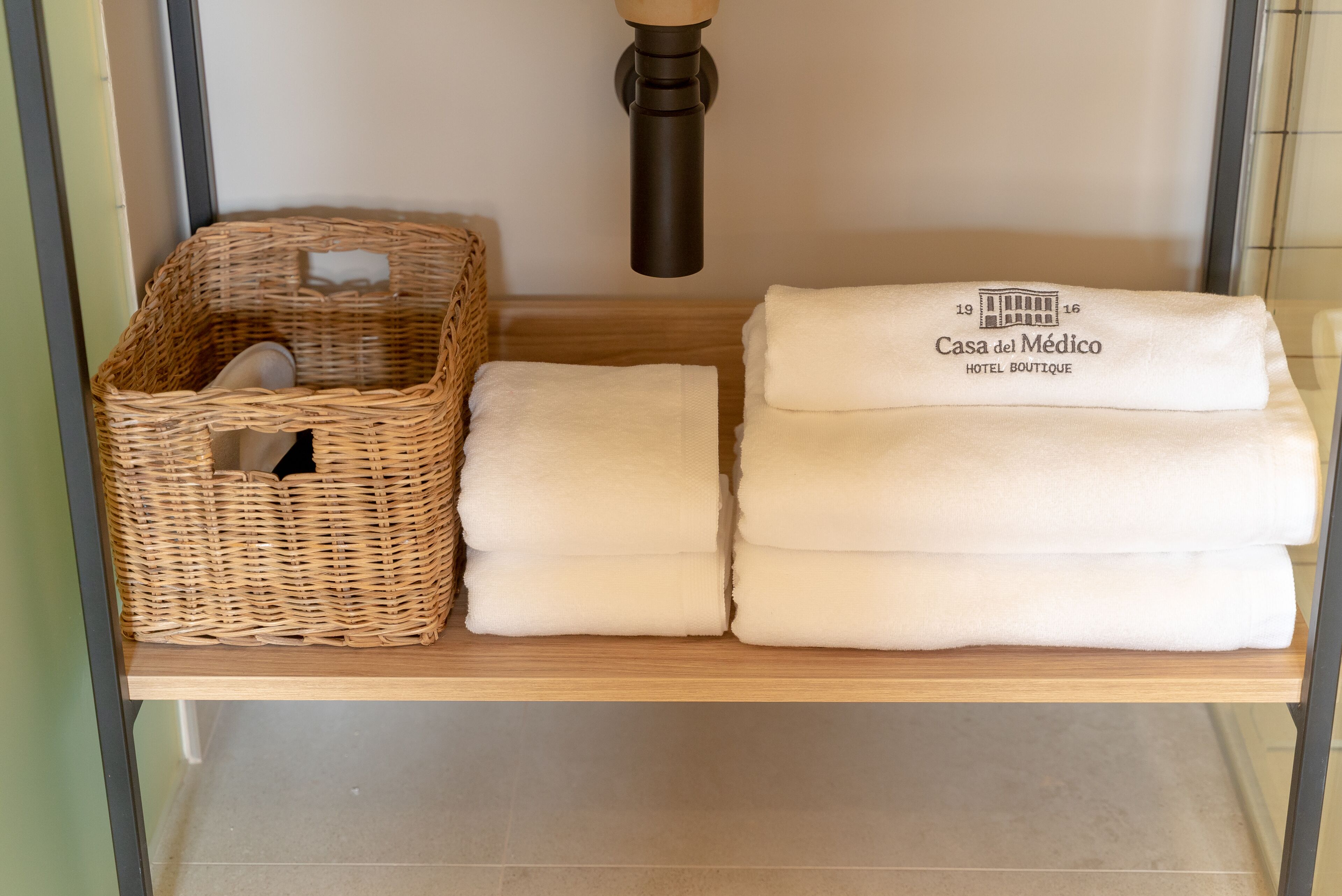 A shelf with a wicker basket and folded white towels.
