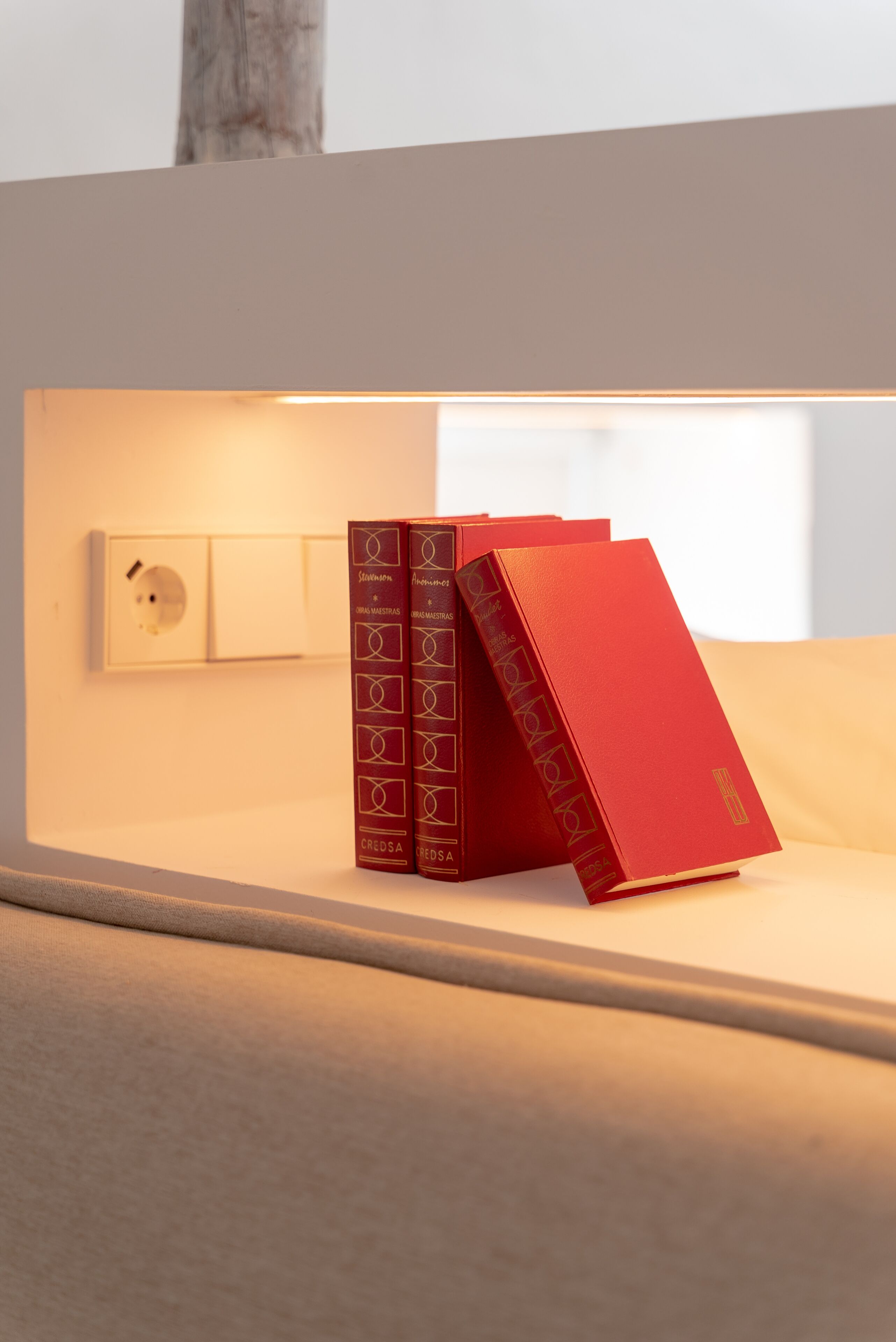 Una estantería con tres libros rojos.
