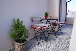Enjoy a tranquil retreat on this balcony with a foldable table, two chairs, and a potted plant.