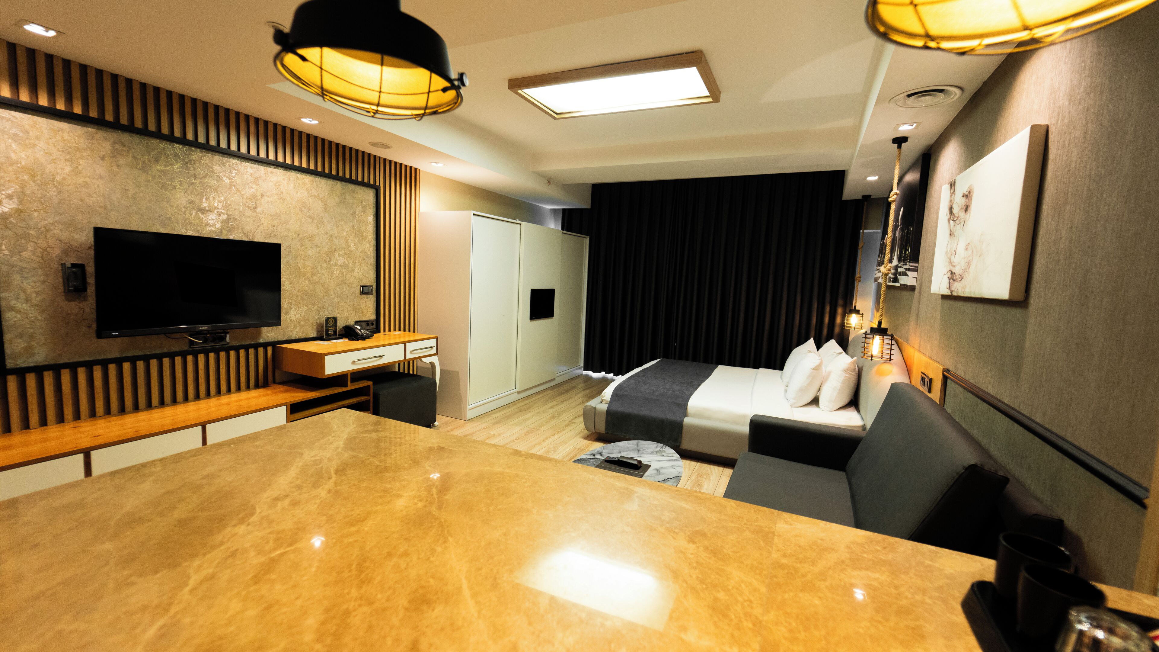 Une chambre d’hôtel moderne dotée d’une table à manger en marbre, d’un téléviseur à écran plat, d’un canapé-lit et d’un bureau avec un téléphone.