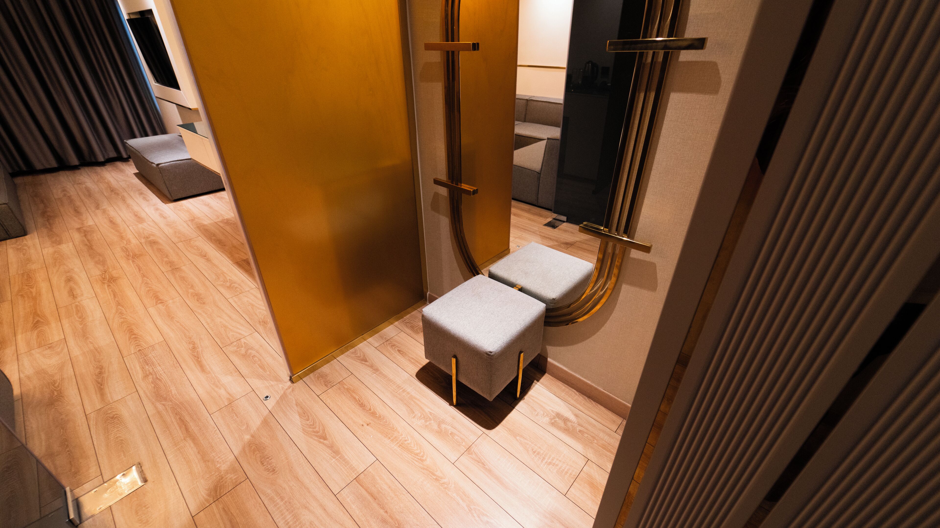A modern bathroom with a wooden floor, a small stool, and a towel rack.