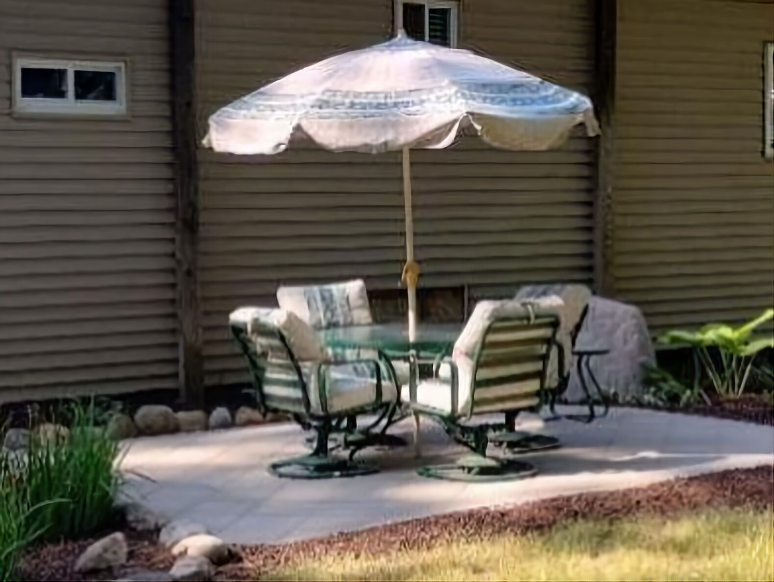 Un patio con una mesa y sillas bajo un paraguas estampado.