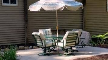Un patio con una mesa y sillas bajo un paraguas estampado.